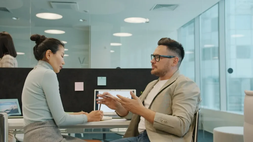 Two colleagues discussing work in a modern office.