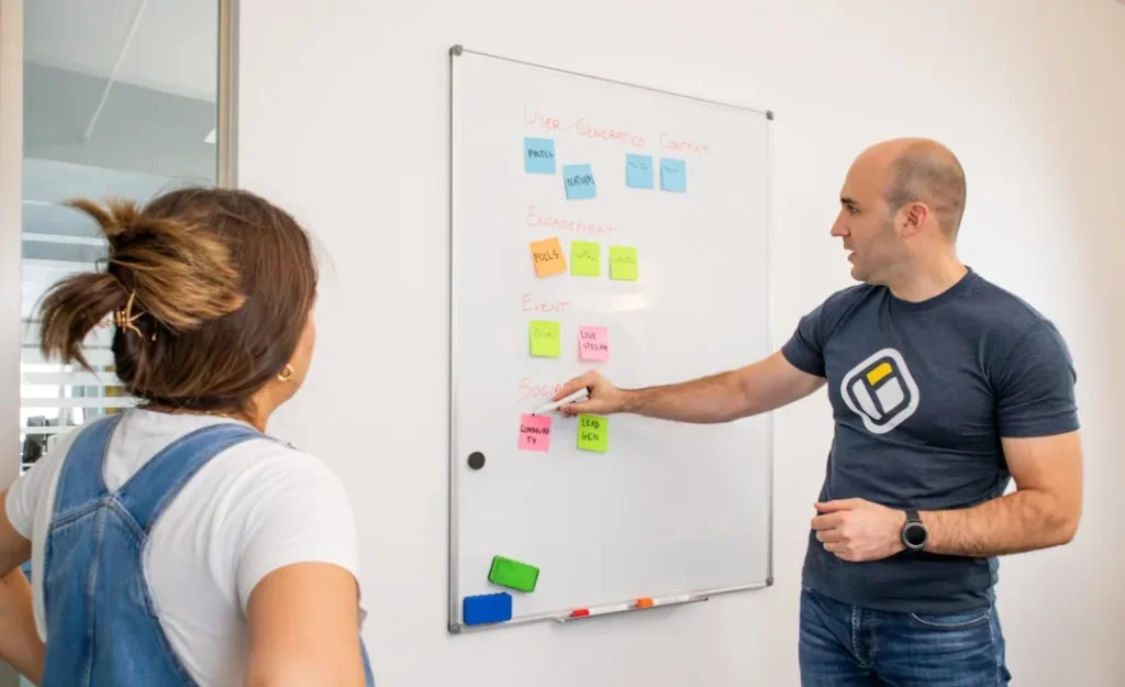 a man and a woman standing in front of a white board