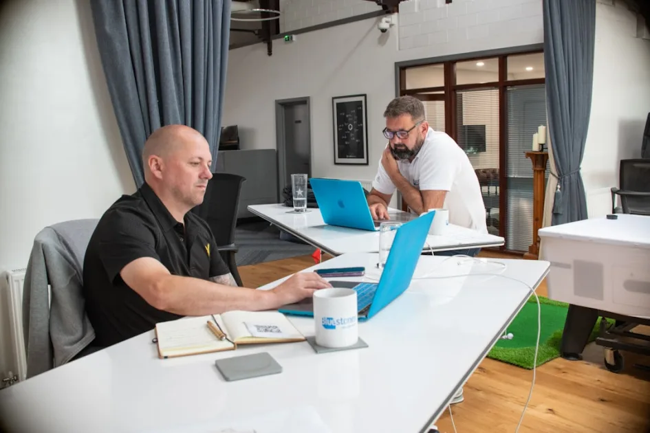 Two men working on laptops in a modern office