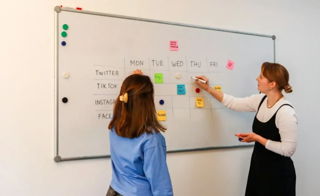 two women are writing on a white board